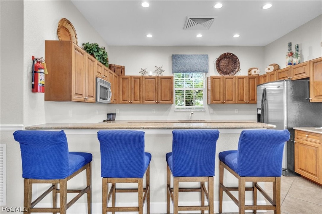 3740 Pebblebrook Ridge Court, Unit 102 Fort Myers, FL 33905 - Photo 35 of 46 a kitchen with stainless steel appliances granite countertop wooden cabinets a dining table and chairs
