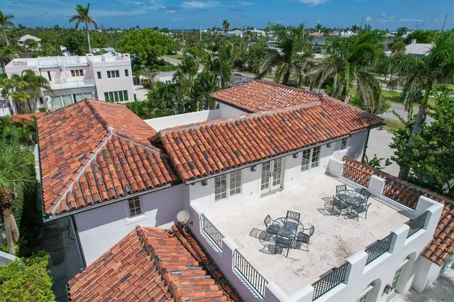 a view of a white house next to a yard with big trees