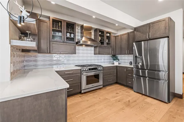 a kitchen with stainless steel appliances kitchen island granite countertop a table chairs and a refrigerator