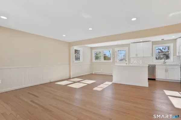 a view of an empty room with a window and wooden floor