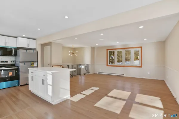 a kitchen with stainless steel appliances granite countertop a refrigerator a stove top oven a sink dishwasher and white cabinets with wooden floor