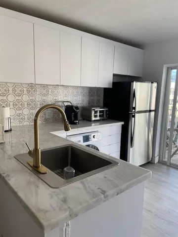 a kitchen with stainless steel appliances a sink a refrigerator a stove a microwave and cabinets