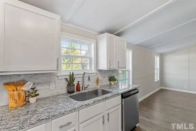 a kitchen with granite countertop a sink a window cabinets and stainless steel appliances