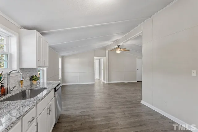 a kitchen with granite countertop a sink cabinets and wooden floor