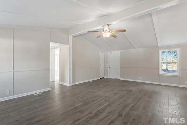 an empty room with wooden floor and ceiling fan