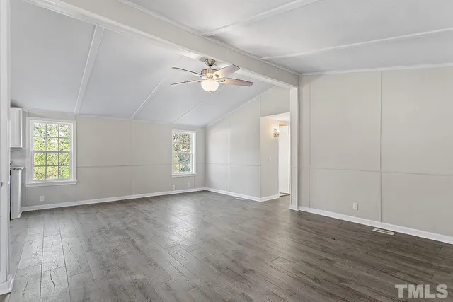 an empty room with wooden floor chandelier fan and windows