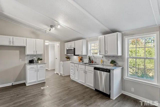 a kitchen with white cabinets and wooden floor