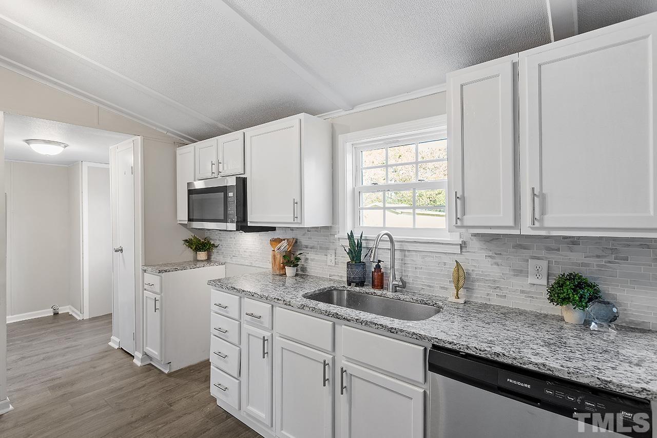 313 Smith Road Smithfield, NC 27577 - Photo 10 of 36 a kitchen with stainless steel appliances granite countertop white cabinets sink and window