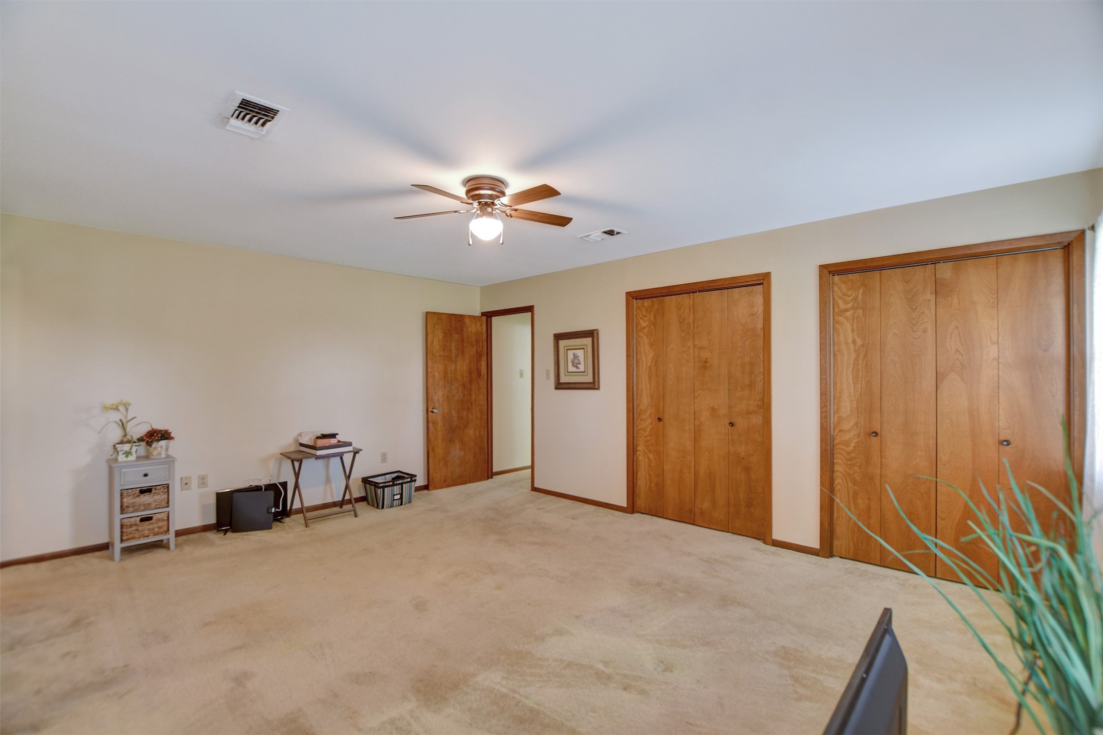 341 South S Loop Bellville, TX 77418 - Photo 21 of 33 This spacious room features neutral carpet, a ceiling fan, and ample natural light. It includes multiple wooden closets for storage and offers a versatile layout.