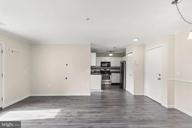 a view of kitchen and empty room with wooden floor