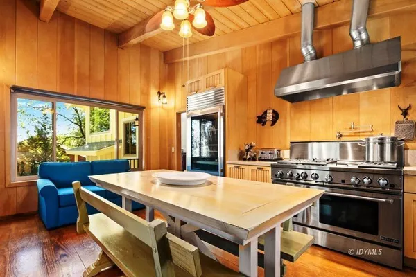 a kitchen with a stove a sink and a dining table with wooden floor