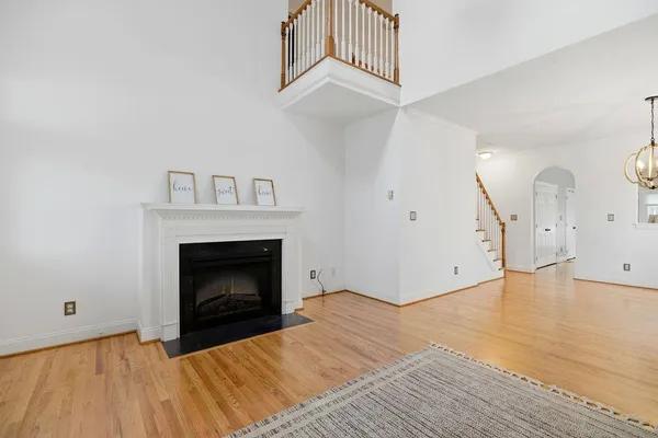 a view of a livingroom with a fireplace a ceiling fan and wooden floor