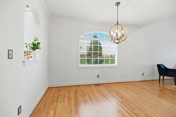 a view of empty room with wooden floor and window