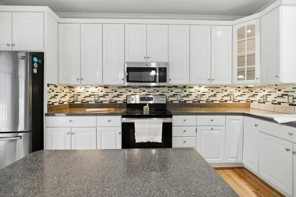 a kitchen with granite countertop white cabinets and stainless steel appliances
