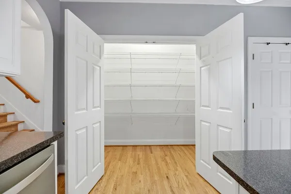 a view of walk in closet and bedroom with wooden floor