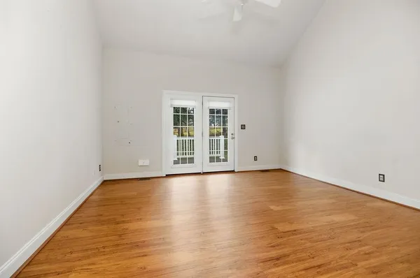 an empty room with wooden floor and windows