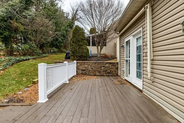 a view of a patio with wooden floor and fence next to a yard