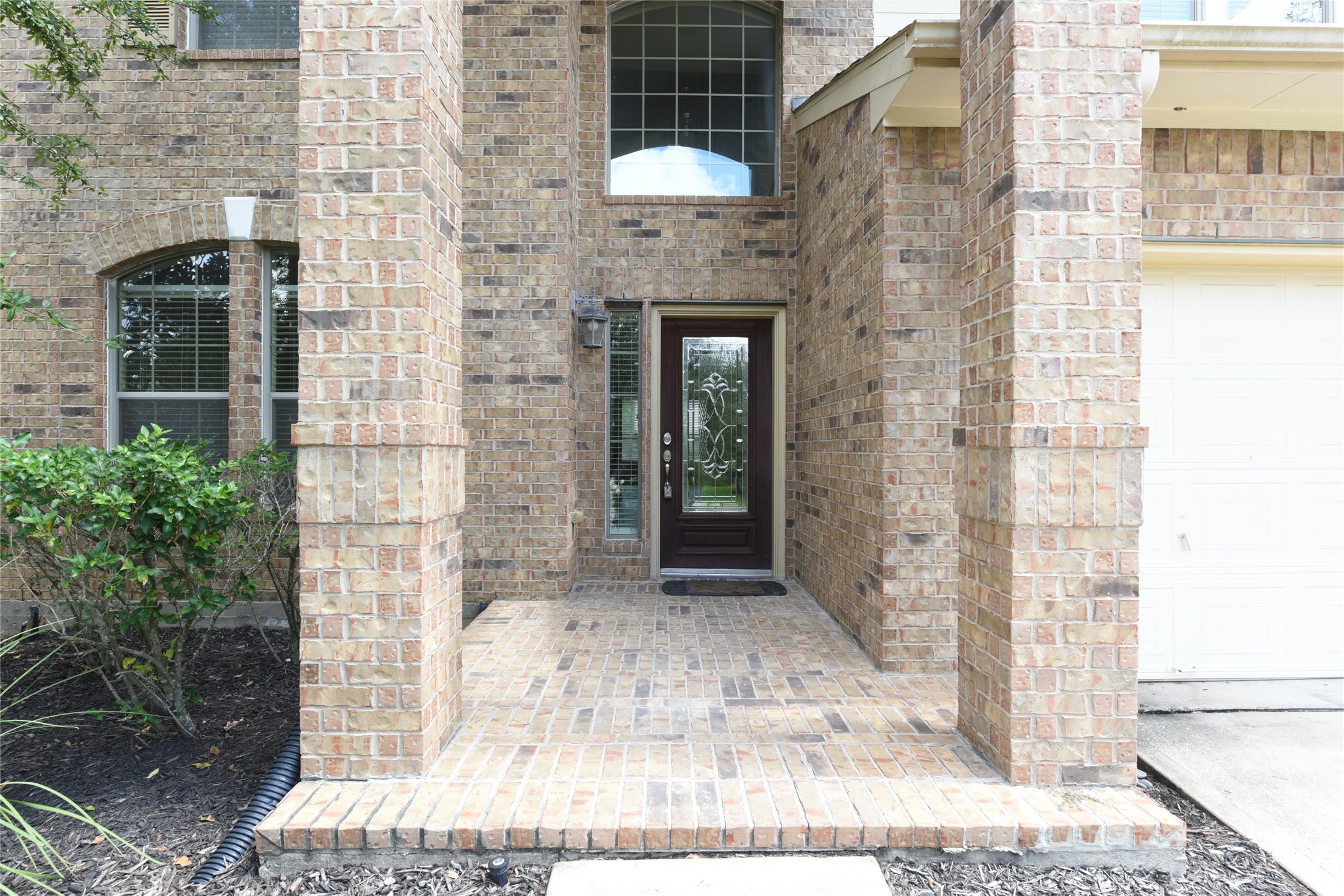 Elegant brick entryway with a covered porch and decorative glass front door, offering a warm welcome to your future home.