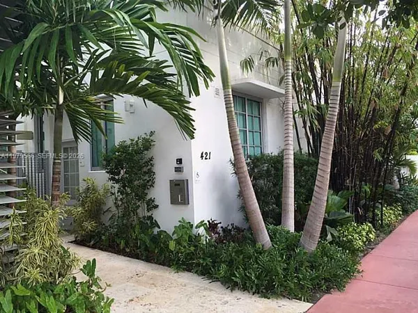a view of a white house with a palm tree next to a yard