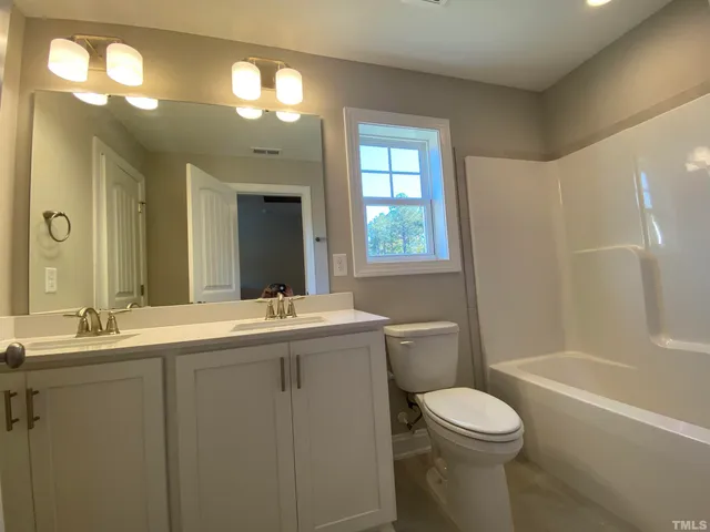 a bathroom with a granite countertop sink mirror vanity and toilet