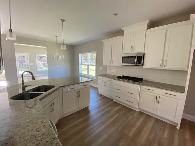 a kitchen with granite countertop a sink stainless steel appliances and white cabinets