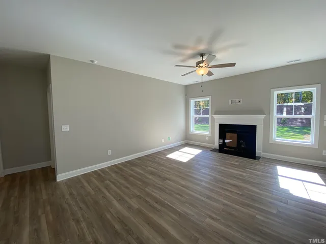 an empty room with windows a fireplace and wooden floor