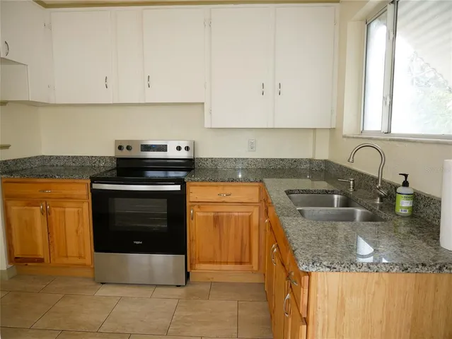 a kitchen with granite countertop a stove sink and cabinets
