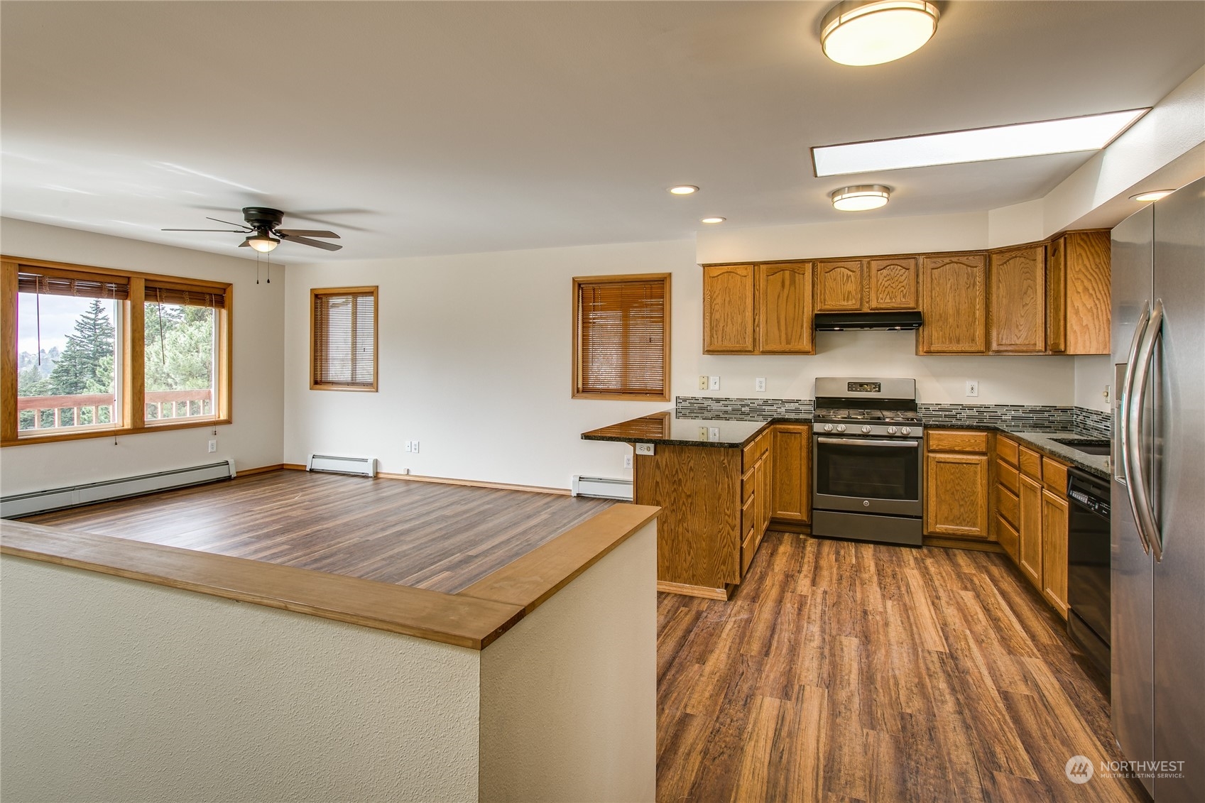 1818 35th Street Bellingham, WA 98229 - Photo 5 of 39 a kitchen with granite countertop a stove top oven a sink dishwasher a dining table and chairs with wooden floor