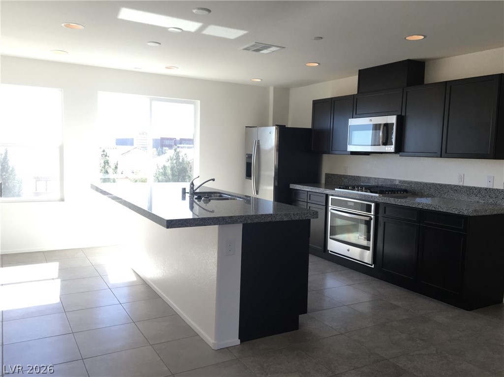 4650 Ranch House Road, Unit 9 North Las Vegas, NV 89031 - Photo 4 of 13 A contemporary kitchen features dark cabinetry, light granite counters, and stainless steel appliances.