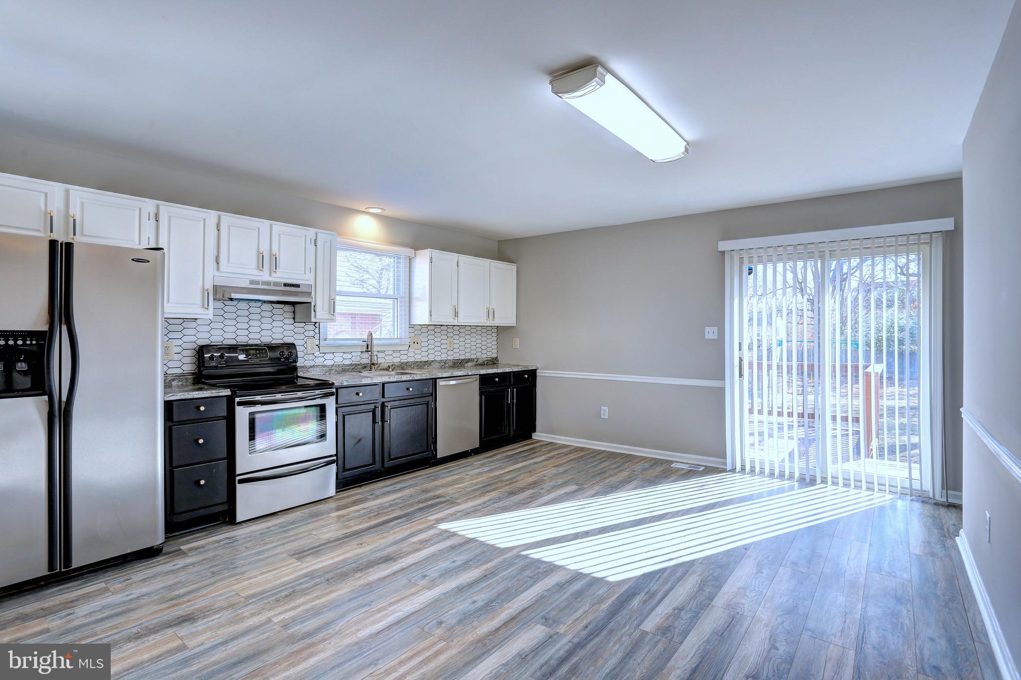 9575 Cissell Avenue Laurel, MD 20723 - Photo 6 of 34 a kitchen with granite countertop a refrigerator and wooden floors