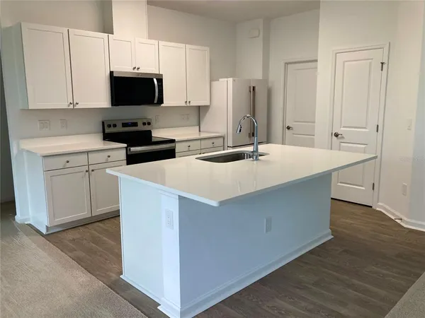 a kitchen with stainless steel appliances a stove a sink and white cabinets