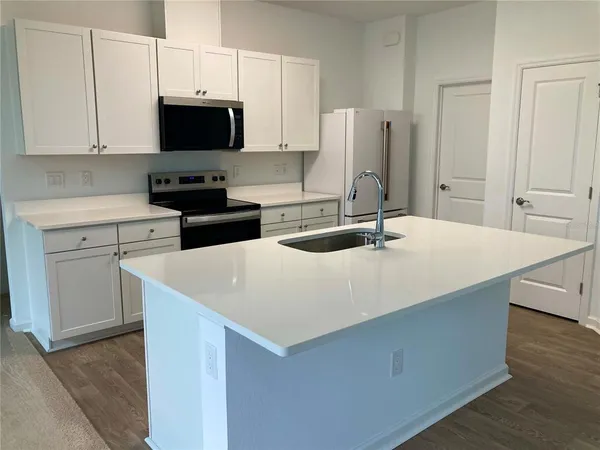 a kitchen with stainless steel appliances white cabinets and a stove a refrigerator with wooden floors