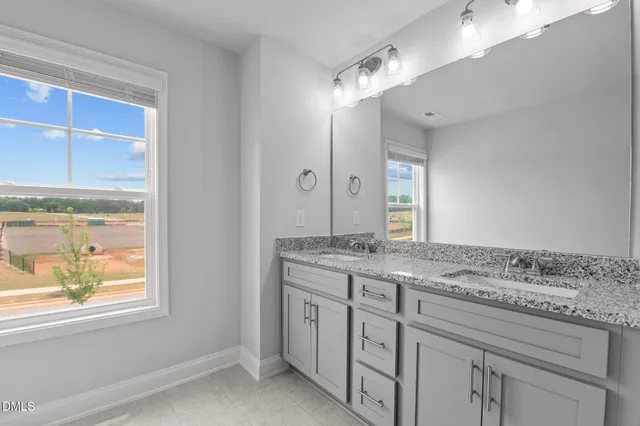 a bathroom with a granite countertop sink mirror and window