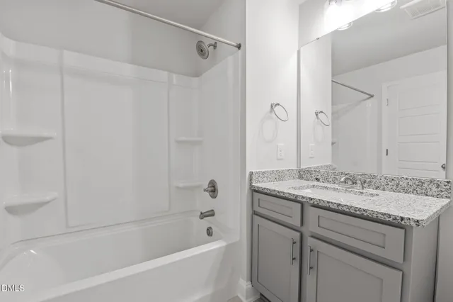 a bathroom with a granite countertop sink a mirror a shower and a bathtub