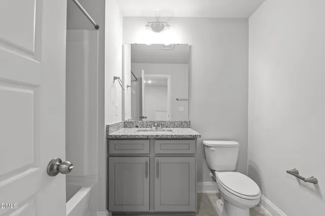 a bathroom with a granite countertop toilet a sink and a mirror