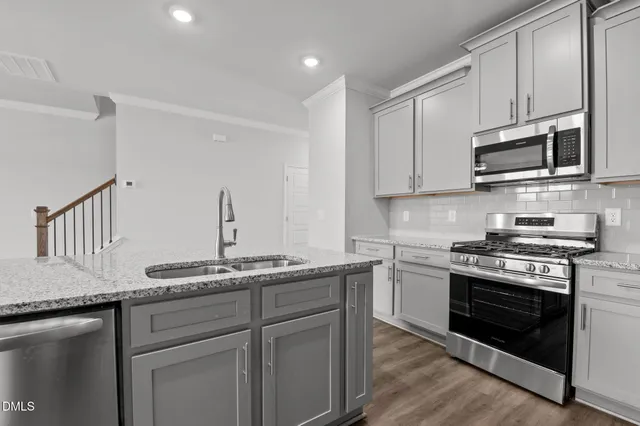a kitchen with stainless steel appliances granite countertop a stove a sink and a microwave