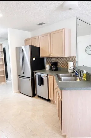 a kitchen with stainless steel appliances granite countertop a sink a stove a refrigerator a washer and dryer