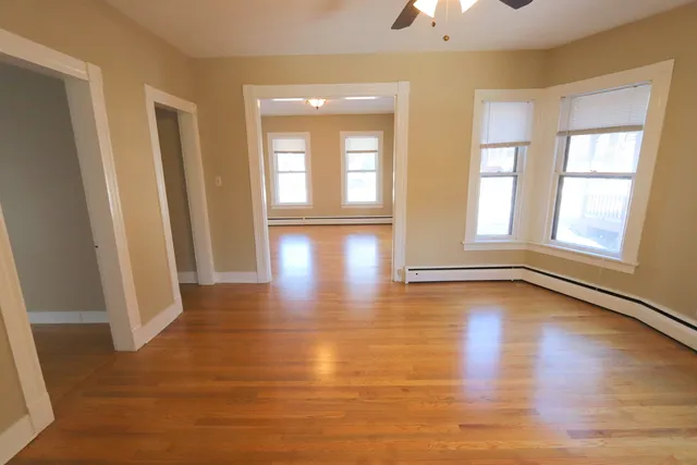 a view of an empty room with wooden floor and a window