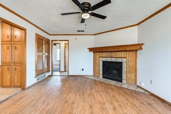 a view of an empty room with wooden floor and a fireplace