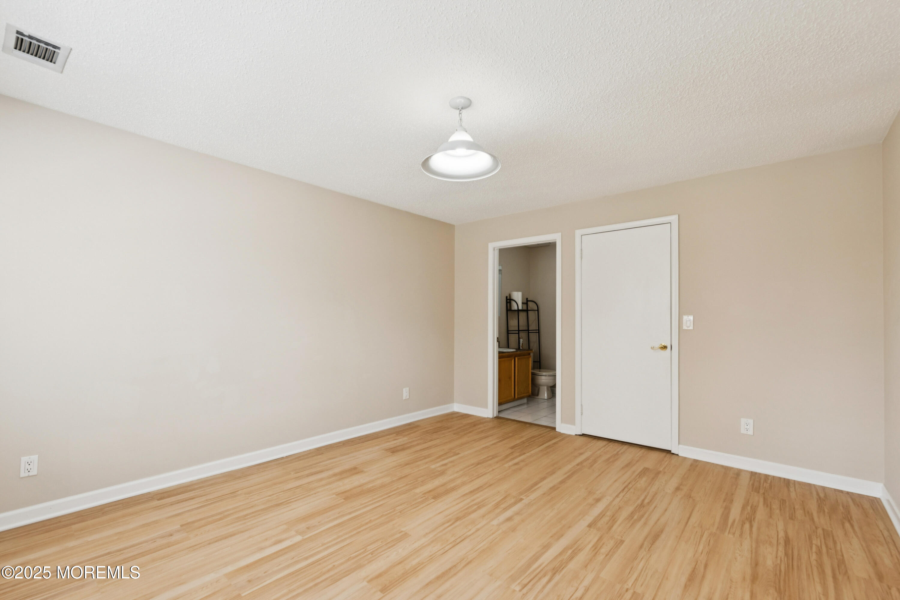 20-3 Austin Court, Unit 7 Freehold, NJ 07728 - Photo 21 of 31 a view of an empty room with wooden floor and fan