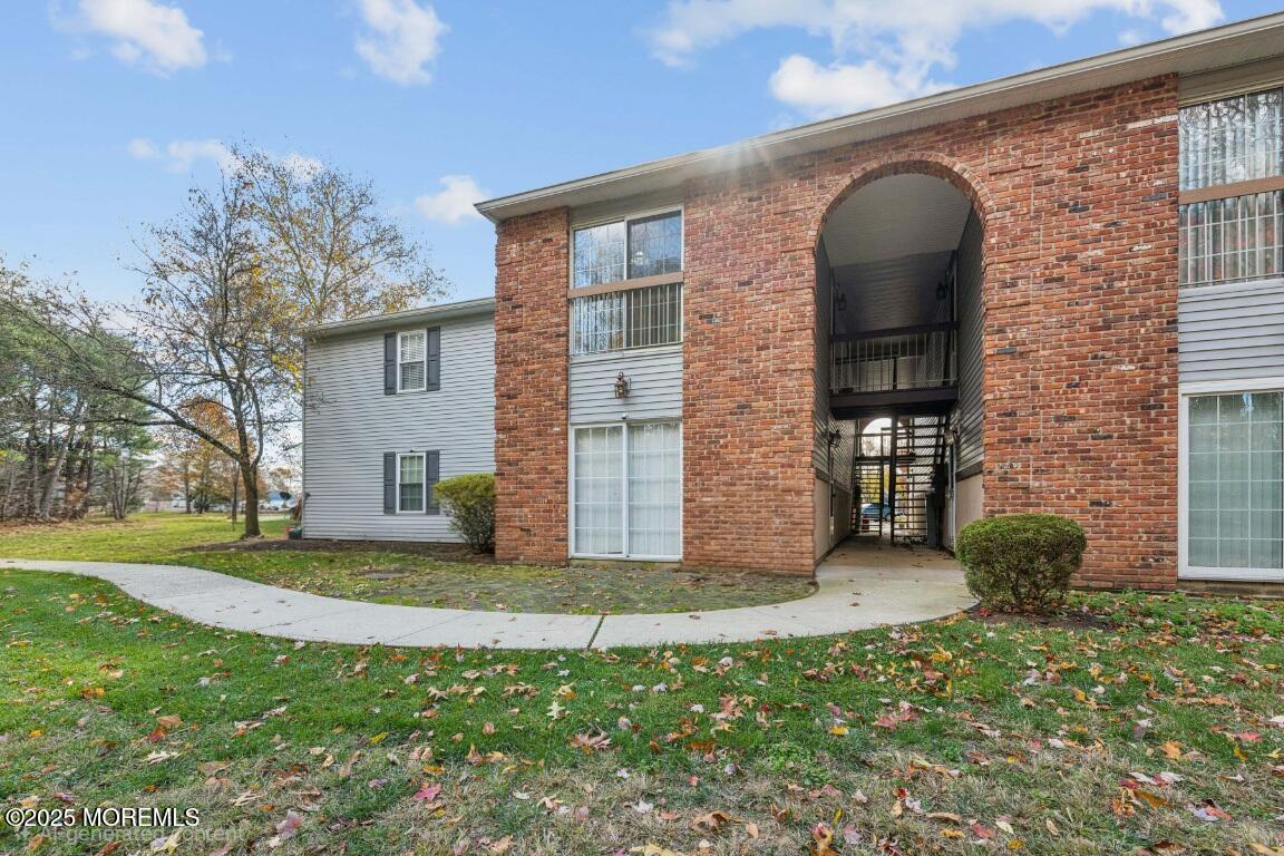 20-3 Austin Court, Unit 7 Freehold, NJ 07728 - Photo 29 of 31 a view of a brick house with a large windows and a yard
