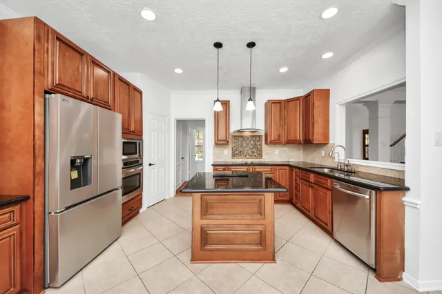 a kitchen with stainless steel appliances granite countertop a sink a stove a refrigerator cabinets and a kitchen island