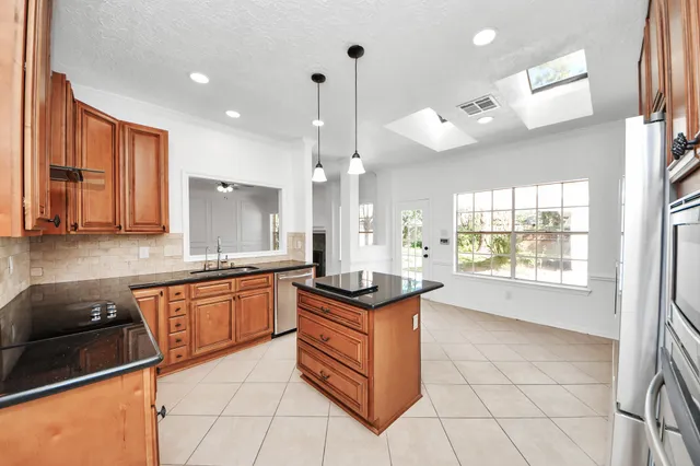 a kitchen with stainless steel appliances granite countertop a stove a sink and a refrigerator with wooden floors