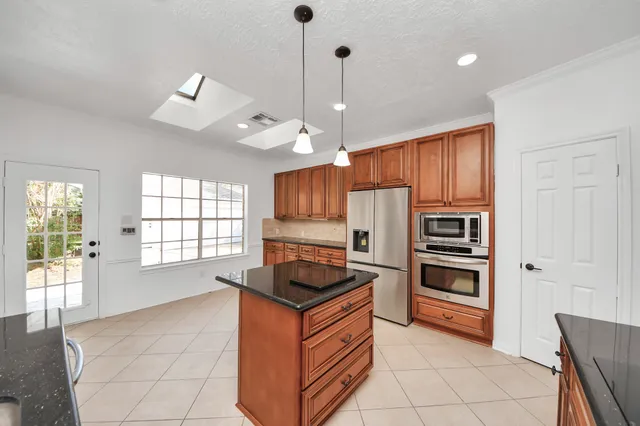 a large kitchen with granite countertop a large counter top stainless steel appliances and cabinets