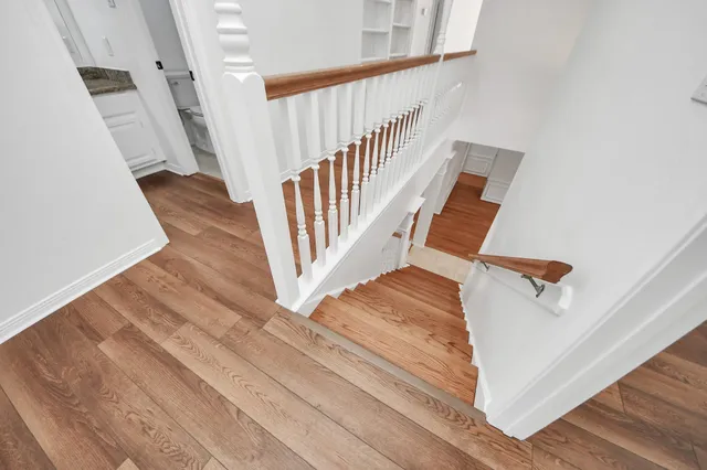 a view of a hallway with wooden floor and a bathroom
