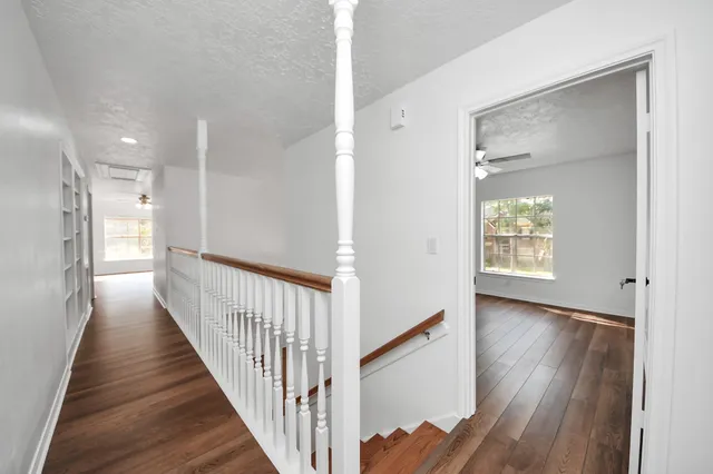a view of empty room with wooden floor and fan