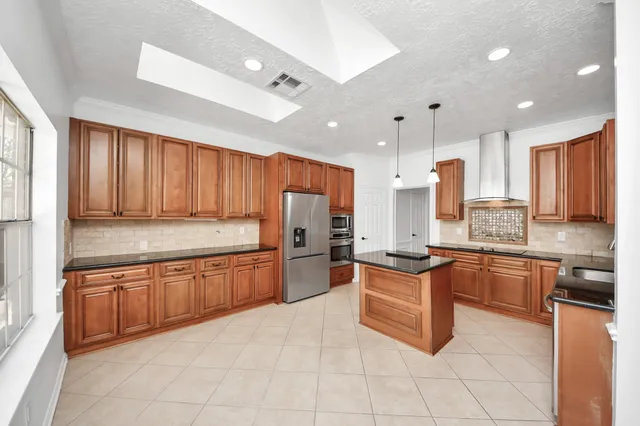 a large kitchen with a large counter top stainless steel appliances and cabinets
