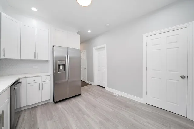 a view of a kitchen with refrigerator and wooden cabinets