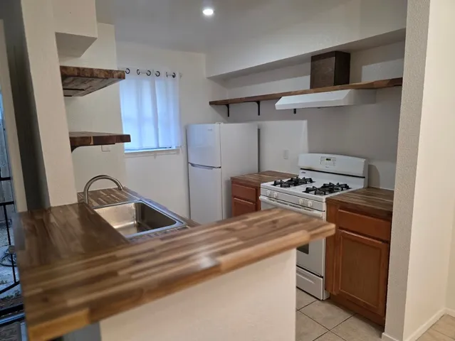 a kitchen with granite countertop a sink stove and refrigerator