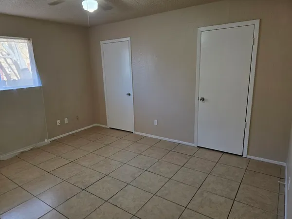 an empty room with a chandelier fan and windows